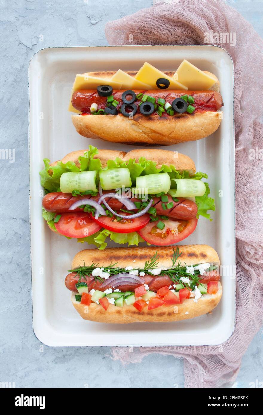 Délicieux hot dogs fraîchement cuits avec saucisses, légumes, fromage et sauce vue de dessus. Banque D'Images