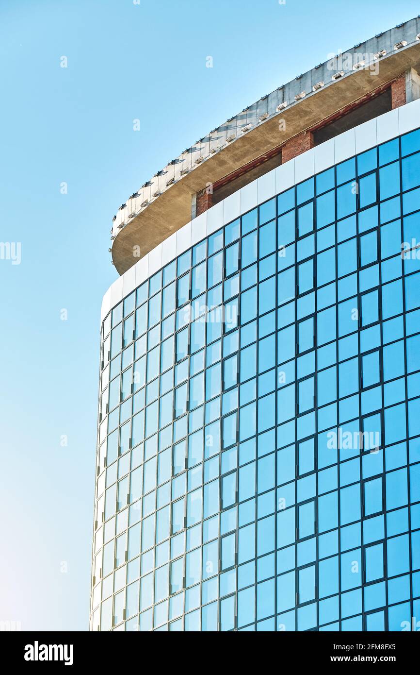 Nouveau bâtiment gratte-ciel haut avec façade en verre brillant et salon sol sur toit plat contre ciel bleu clair sur tranquille jour ensoleillé Banque D'Images