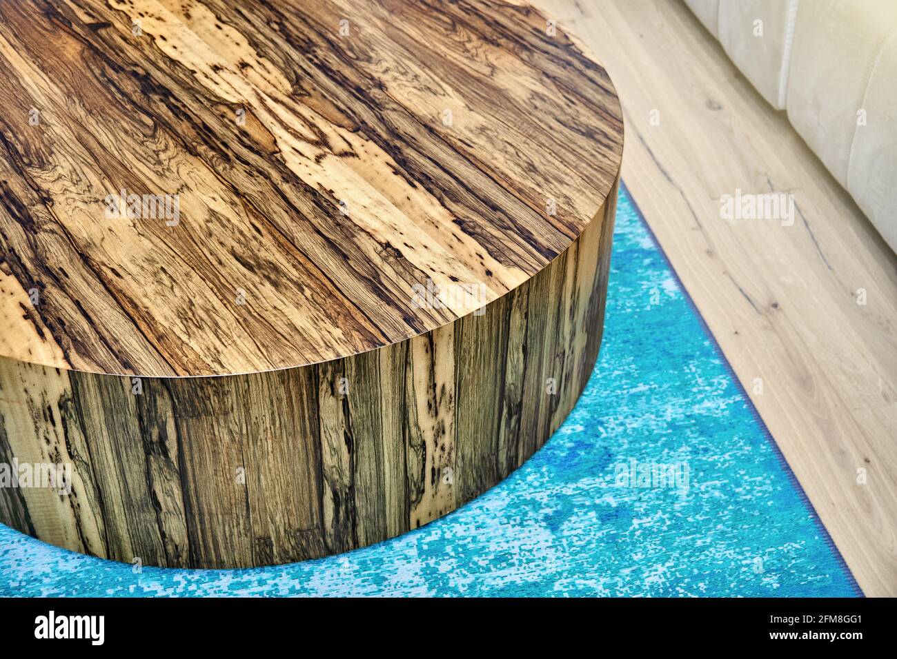 Élégante table à café ronde texturée contemporaine en contreplaqué et Placage naturel Ofram noir sur moquette bleue dans la chambre Banque D'Images