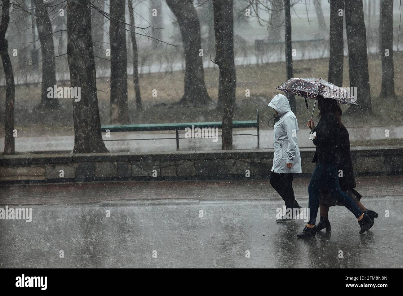 un garçon solitaire marche sous la pluie dans un capot. mauvaise humeur en raison du mauvais temps. pieds et vêtements mouillés. oubliez le parapluie à la maison en saison des pluies Banque D'Images