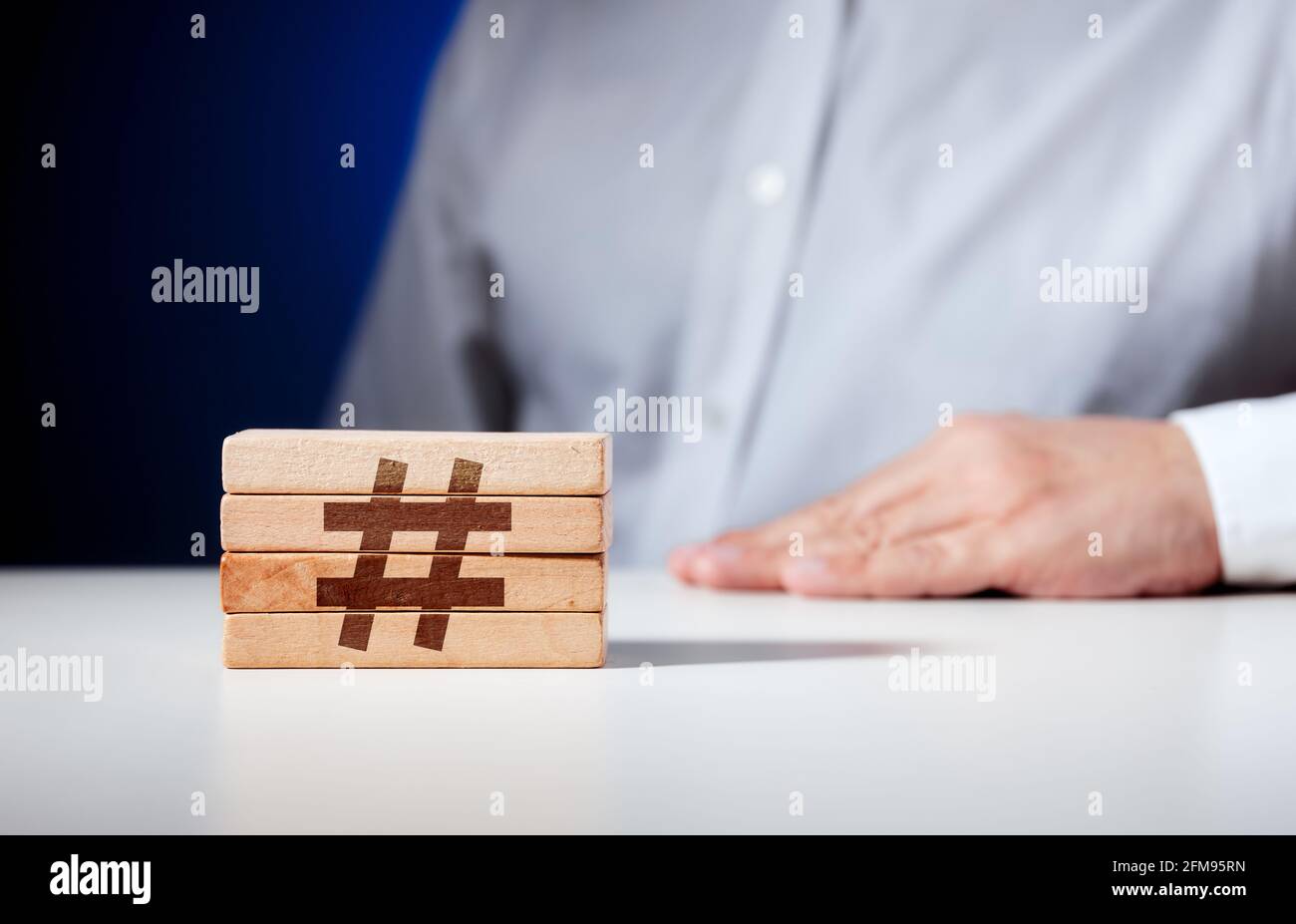 Icône hashtag sculptée sur des blocs de bois avec un homme d'affaires sur le fond. Concept de marketing sur les médias sociaux d'entreprise. Banque D'Images