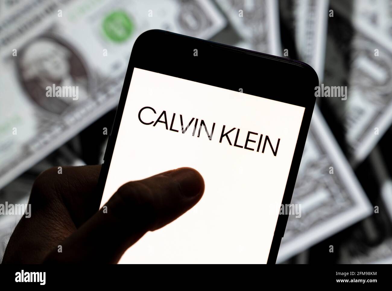 Sur cette photo, le logo de la marque de mode américaine Calvin Klein est affiché sur un smartphone avec une devise en dollars américains (USD) en arrière-plan. Banque D'Images
