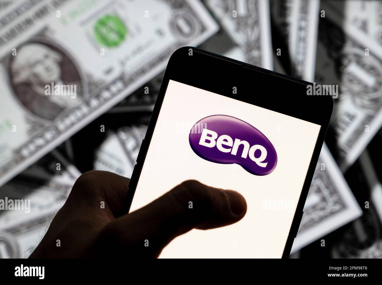 Sur cette photo, le logo Benq de la société multinationale taïwanaise de technologie électronique est affiché sur un smartphone avec une devise en USD (dollar des États-Unis) en arrière-plan. Banque D'Images