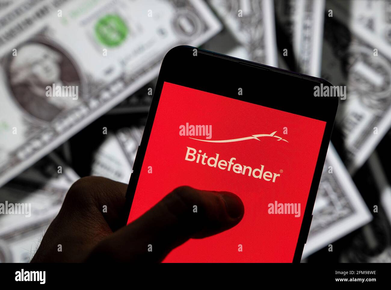Sur cette photo, le logo de la société roumaine de cybersécurité et d'anti-virus Bitdefender s'affiche sur un smartphone avec une devise américaine (USD) en arrière-plan. Banque D'Images