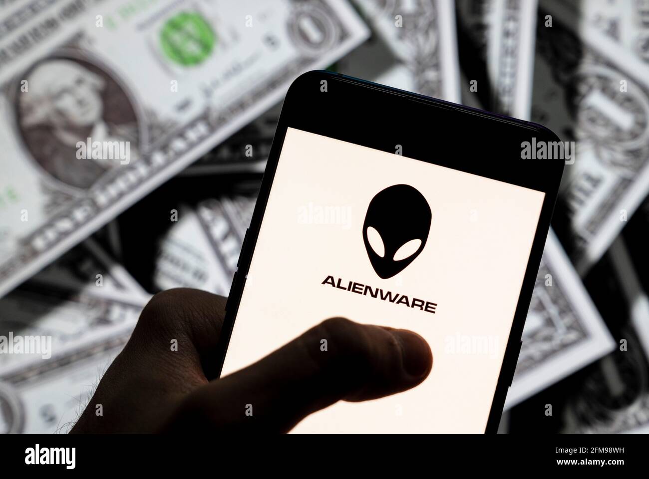 Dans cette illustration, le logo Alienware de la filiale américaine de Dell, visible sur un smartphone avec une devise en USD (dollar américain) en arrière-plan. Banque D'Images