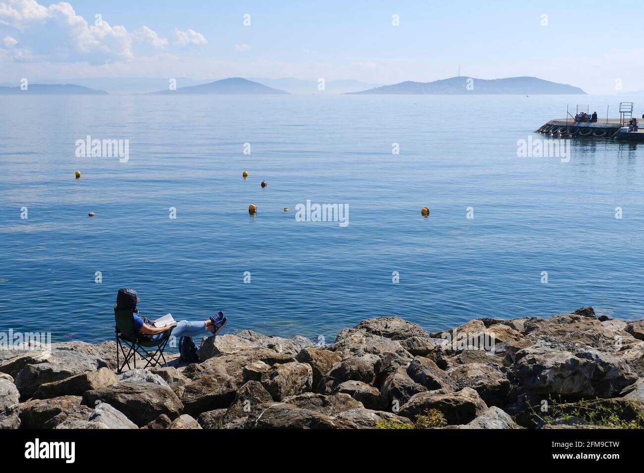 Istanbul, Turquie - 21 avril 2021 : UNE jeune femme moderne lit son livre sur les rochers et profite du paysage des îles du Prince depuis Suadiye Costli Banque D'Images