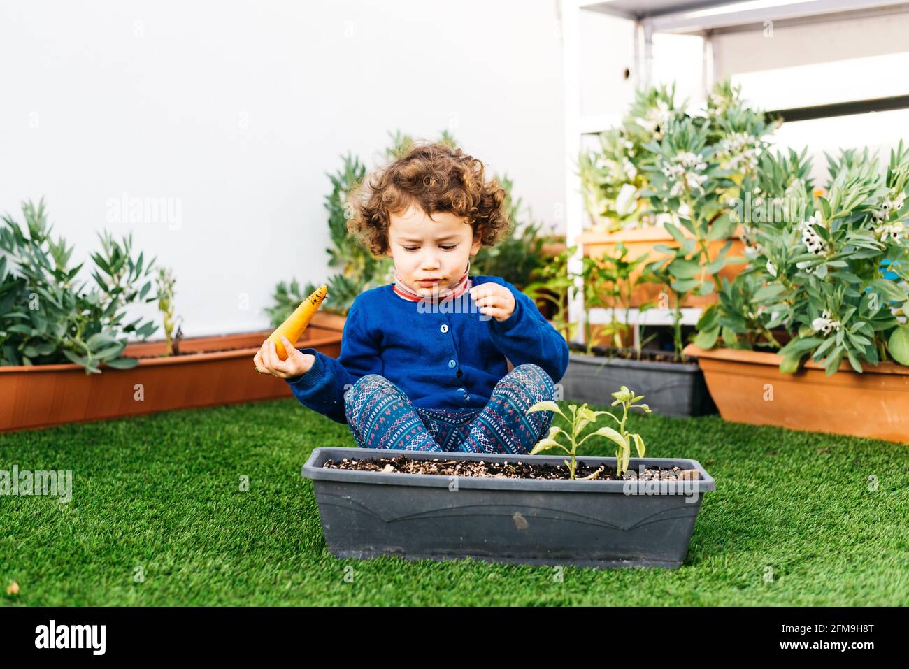 Une petite fille joue dans le jardin pour planter des plantes dans un pot. Banque D'Images