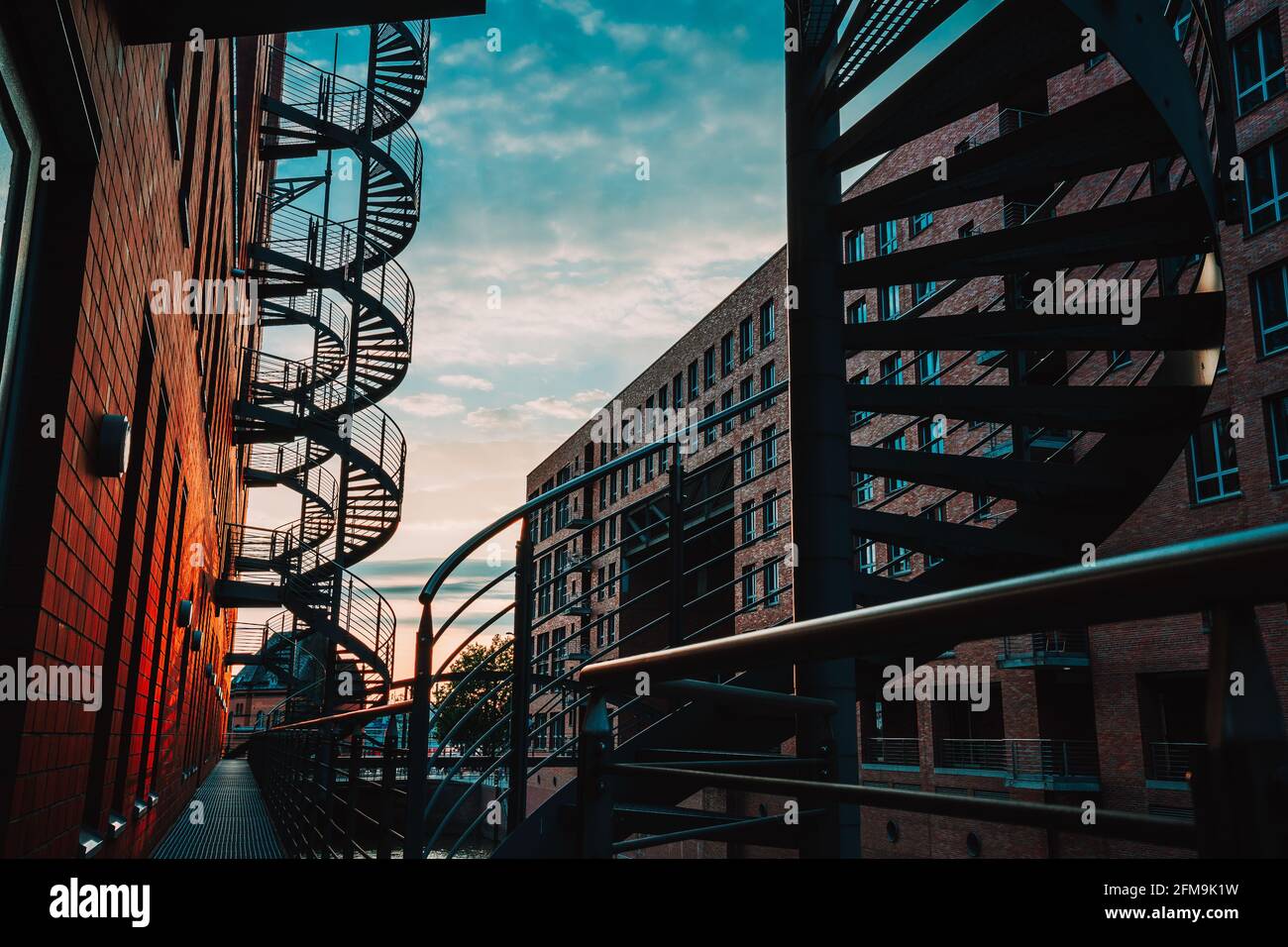 Escaliers en spirale dans l'ancien entrepôt. Bâtiments étroits en canal et briques rouges de Speicherstadt à Hambourg. Après le coucher du soleil. Banque D'Images