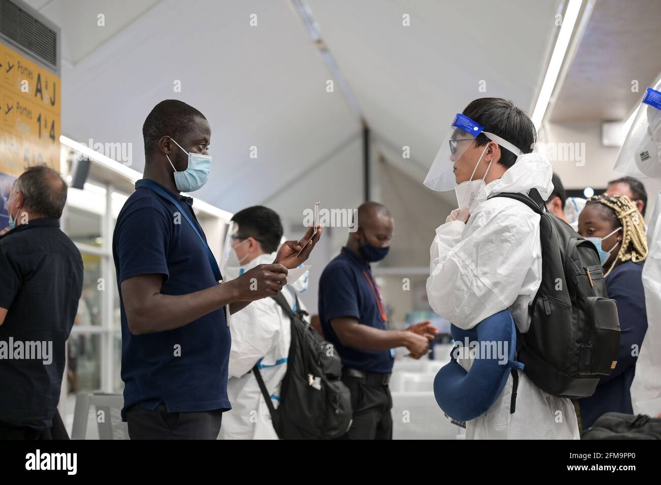 CÔTE D'IVOIRE, Abidjan, aéroport, voyageur chinois avec protection pendant Corona temps de pandémie à la porte d'embarquement à Paris, contrôle de passeport / ELFENBEINKÜSTE, Abidjan, Flughafen, Chinesische Reisende à Schutzkleidung während Corona Pandemie Banque D'Images