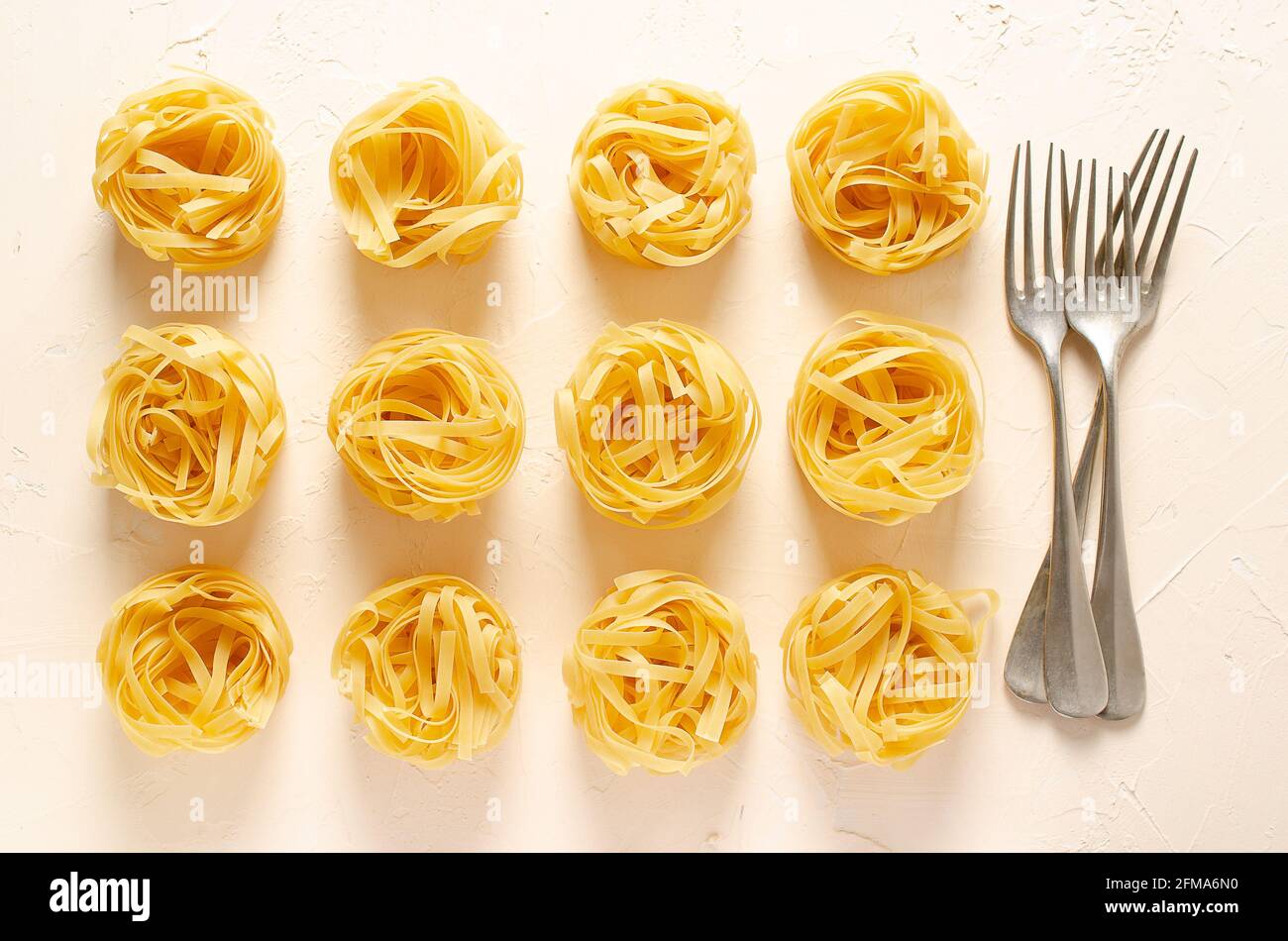 Nids de pâtes de fettuccine avec trois fourchettes sur un fond clair. Banque D'Images