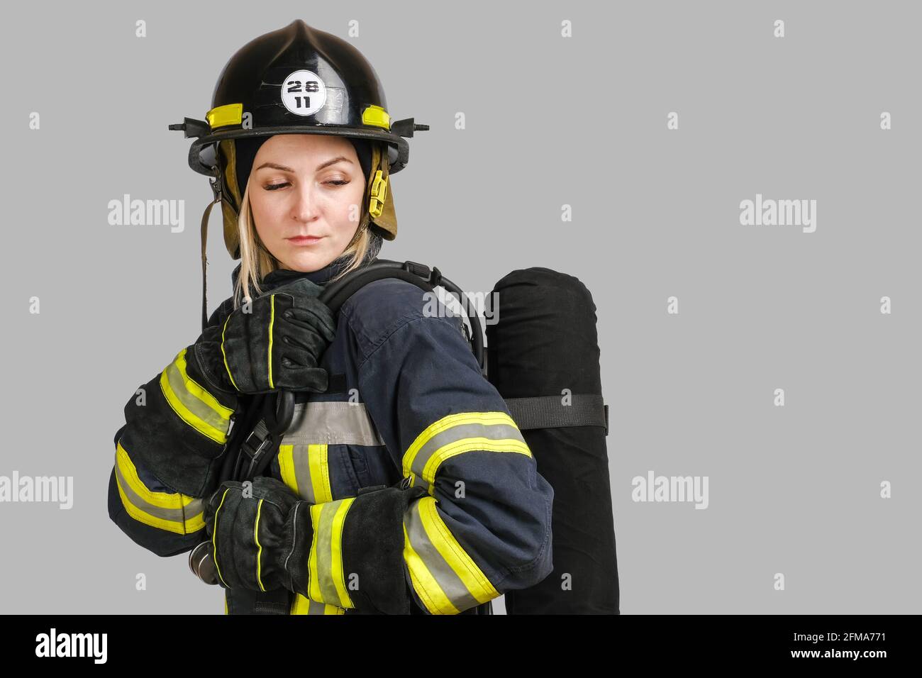 Femme en uniforme de pompier posant en profil avec l'air réservoir Banque D'Images