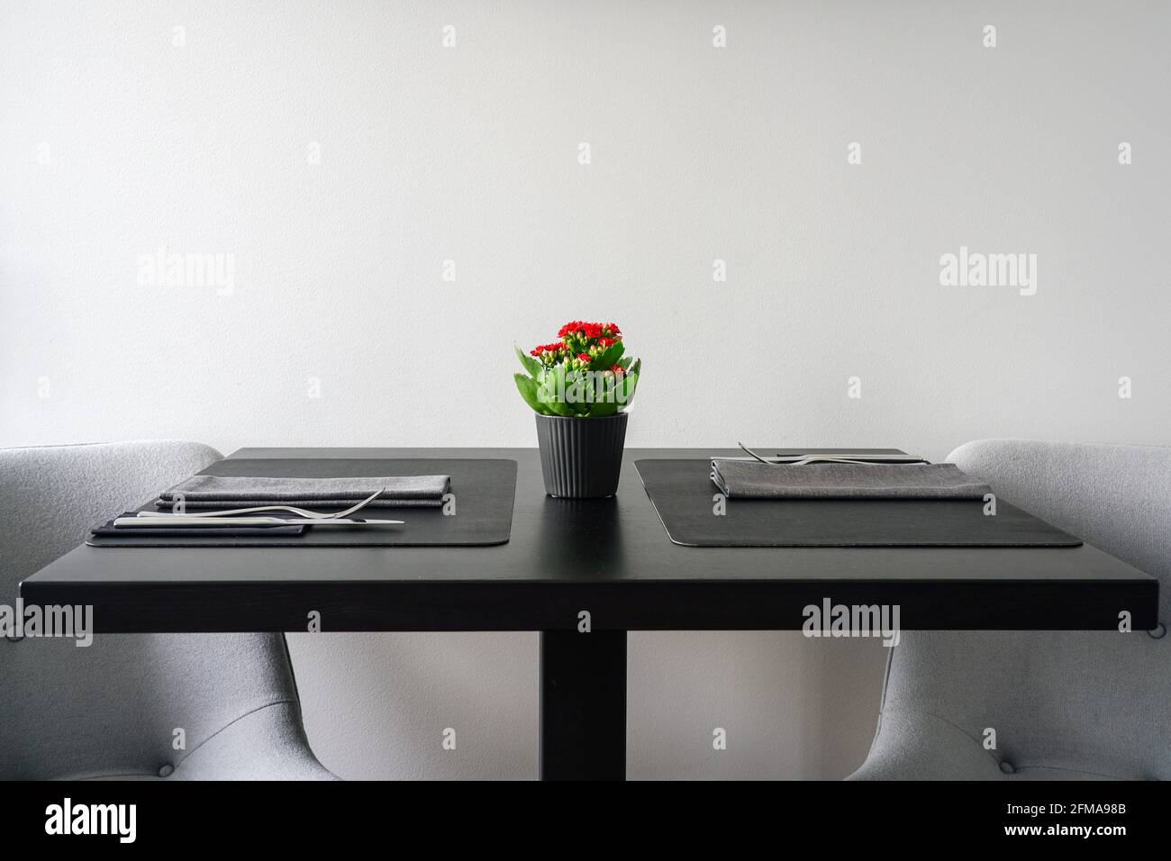 vue latérale d'une table noire avec un pot de fleurs et des couverts avant le dîner dans une atmosphère romantique Banque D'Images