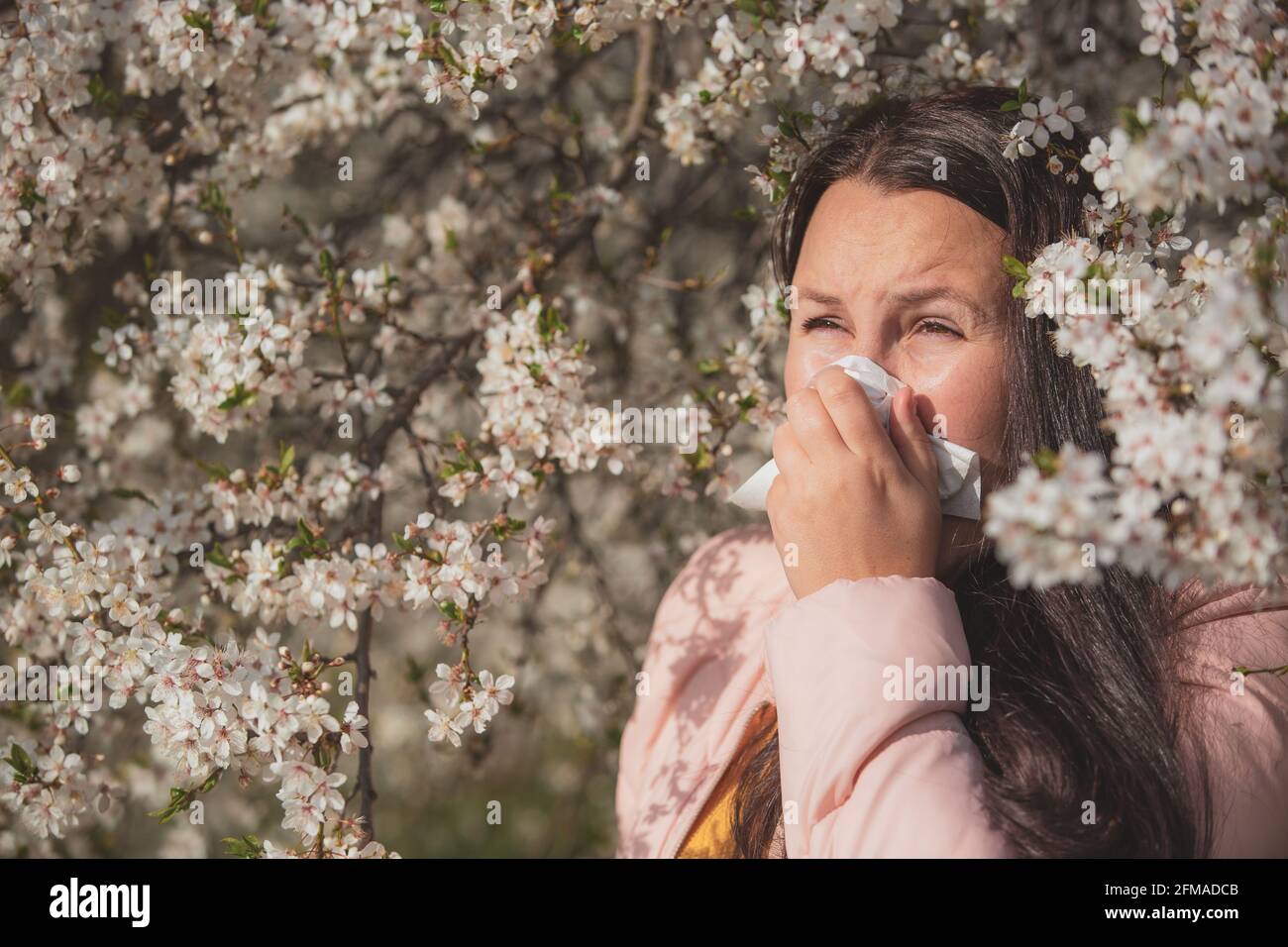 Jolie jeune femme brune avec une forte réaction allergique au printemps, éternuant avec un papier absorbant, concept de soins de santé Banque D'Images