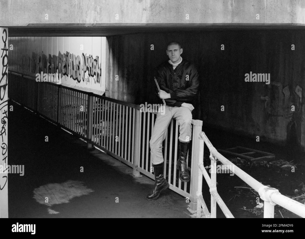 jeune homme skinhead debout dans les graffitis couvert ville faiblement éclairée pneu de retenue de passage inférieur central en fonte années 1990 angleterre royaume-uni Banque D'Images
