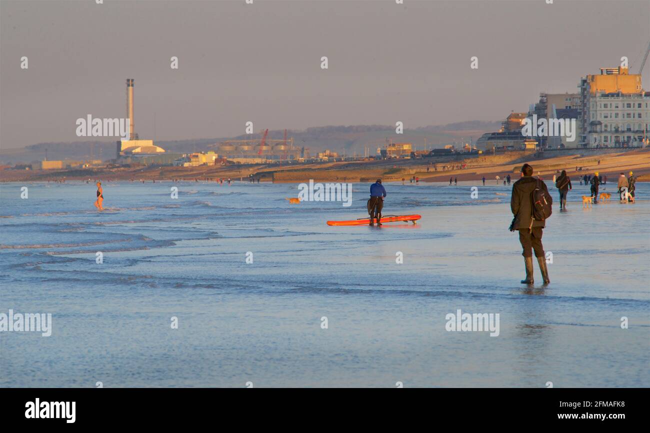 Les gens se promènent tôt le matin sur la plage à marée basse. Brighton & Hove, Sussex, Angleterre, Royaume-Uni. Vers l'ouest en direction de Shoreham, la centrale électrique au loin. Banque D'Images