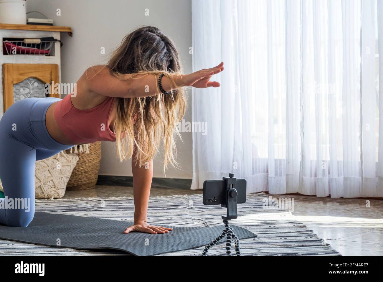 Photo d'une femme de fitness travaillant sur un tapis de yoga et utilisant un téléphone portable. Adapter la jeune femme en utilisant le téléphone portable tout en faisant de l'exercice à la maison. Créateur de contenu moderne des gens d'affaires en ligne Internet Banque D'Images