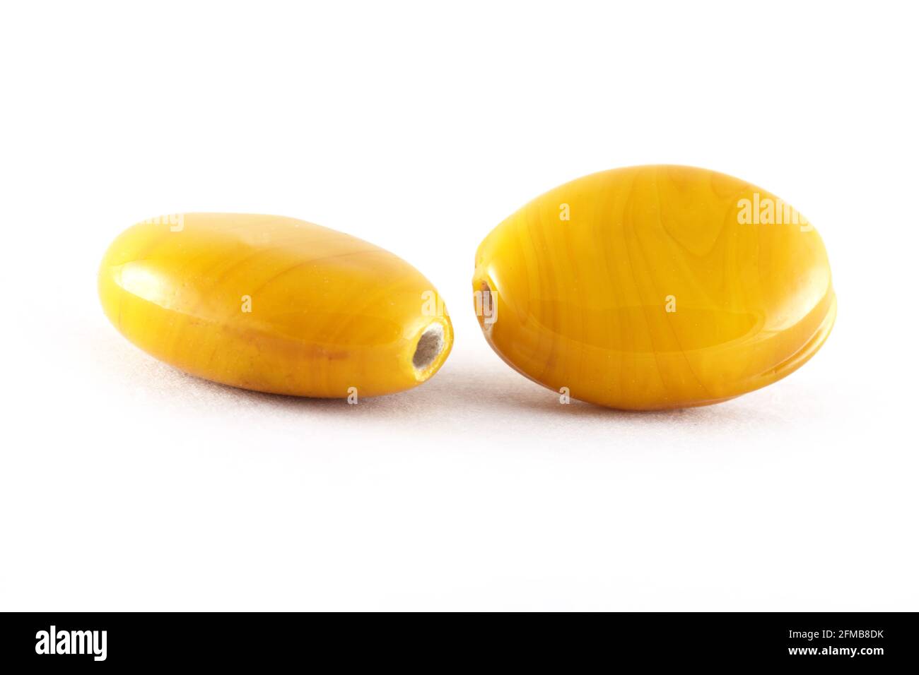 Gros plan de perles jaunes sur fond blanc. Perles ovales, fond ou texture des perles. Macro,utilisé pour la finition des vêtements de mode. Faire des perles Banque D'Images