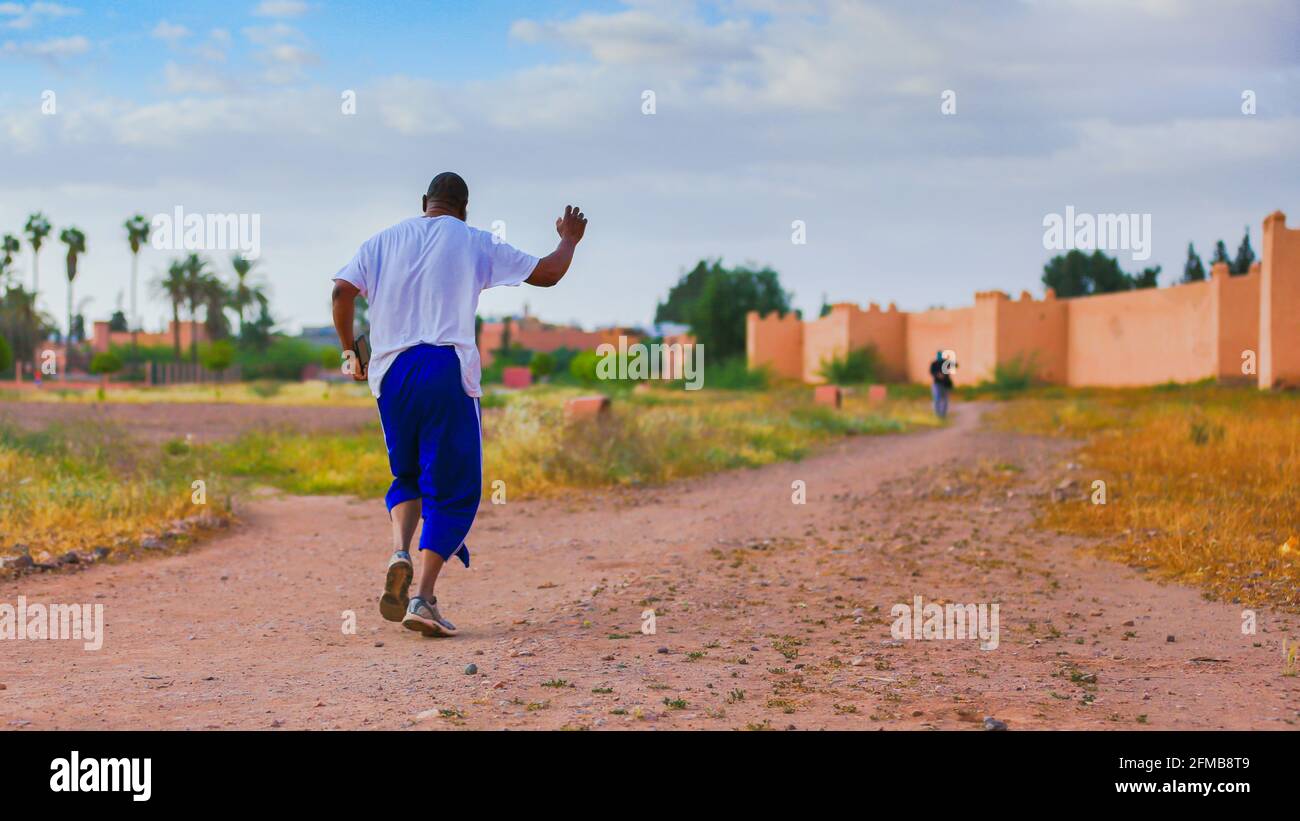 Marrakech, Maroc - 24 AVRIL 2021 : UN homme qui court près du grand mur de la vieille médina de Marrakech Banque D'Images
