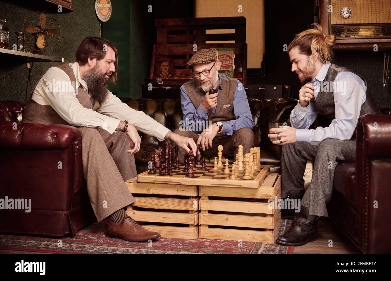 Trois hommes jouant aux échecs dans le barbershop Banque D'Images