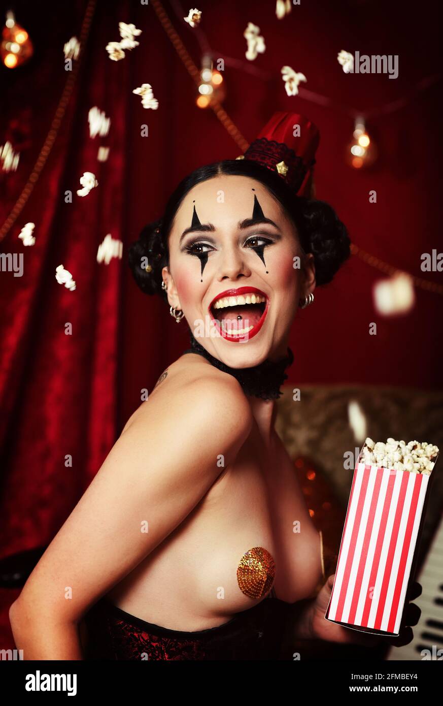 Jeune femme comme arlequin sexy avec pop-corn Banque D'Images