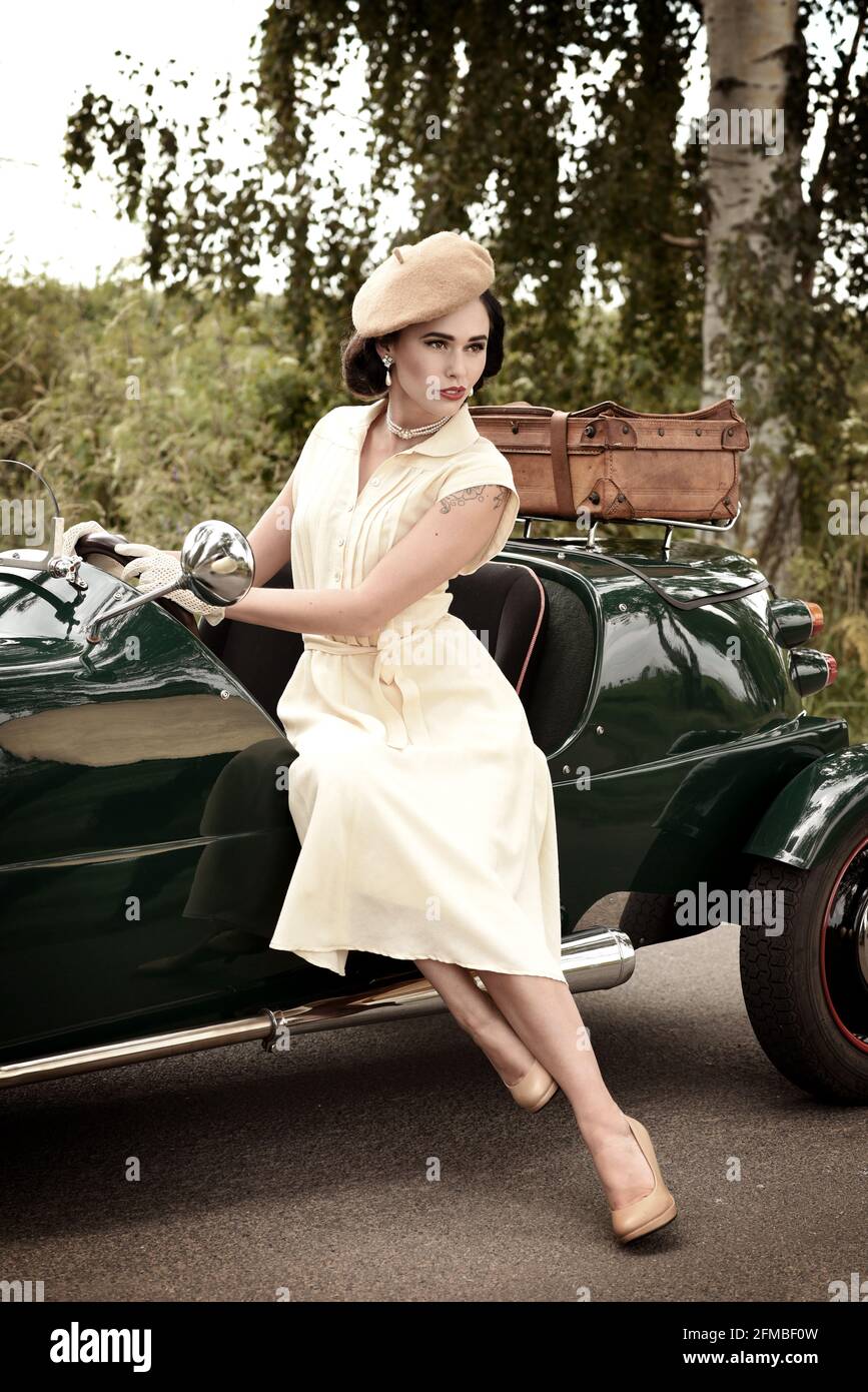 Jeune femme de style des années 1940 avec une voiture vintage dans British Racing Vert Banque D'Images