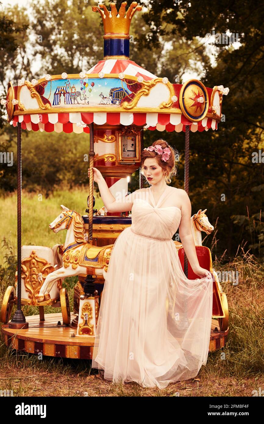 Jeune femme aux cheveux rouges et aux taches de rousseur sur une nostalgique carrousel Banque D'Images