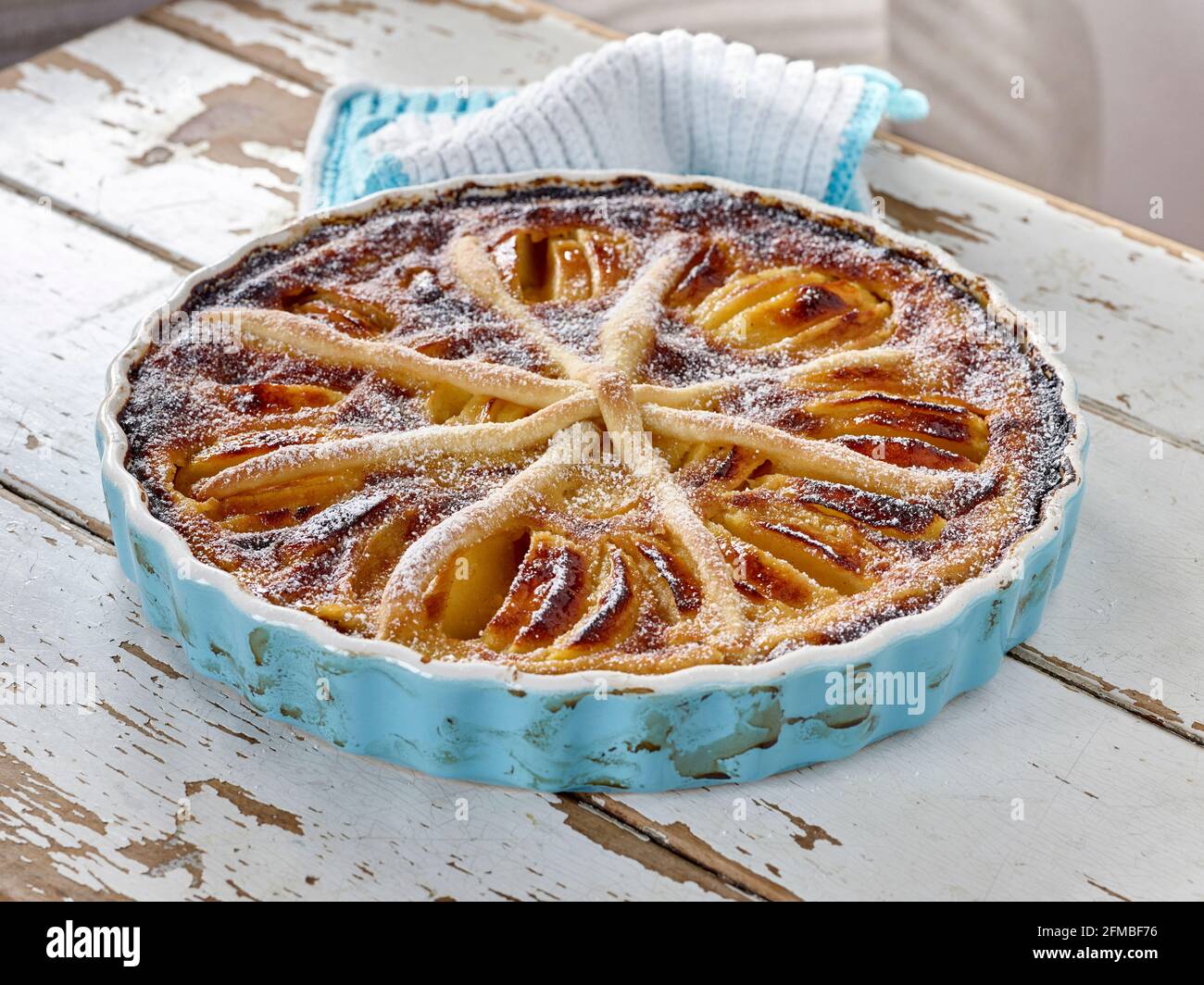 Tarte aux pommes « Alsatian-Art » cuite dans une tarte bleu clair forme avec porte-pots à crochetées bleu clair et blanc Banque D'Images