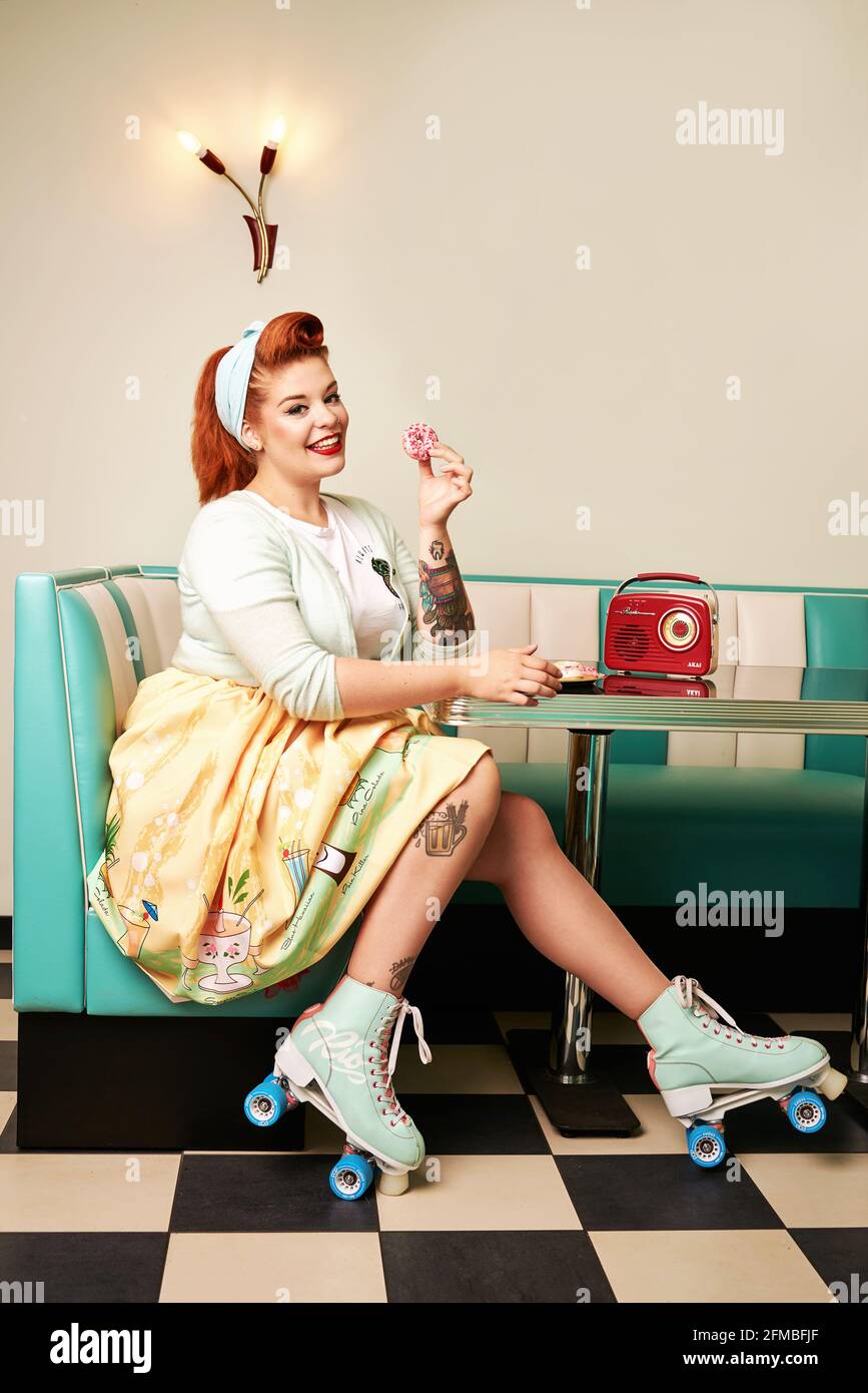 Jeune femme avec cheveux rouges et patins à roulettes bar à lait rétro Banque D'Images