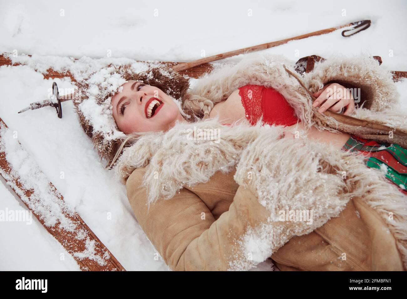 Modèle blond aux courbes avec vieux skis en bois dans la neige Banque D'Images
