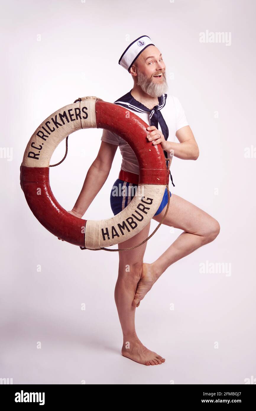 Homme avec une barbe complète comme marin de petit garçon dans un regard maritime avec une bouée de sauvetage Banque D'Images