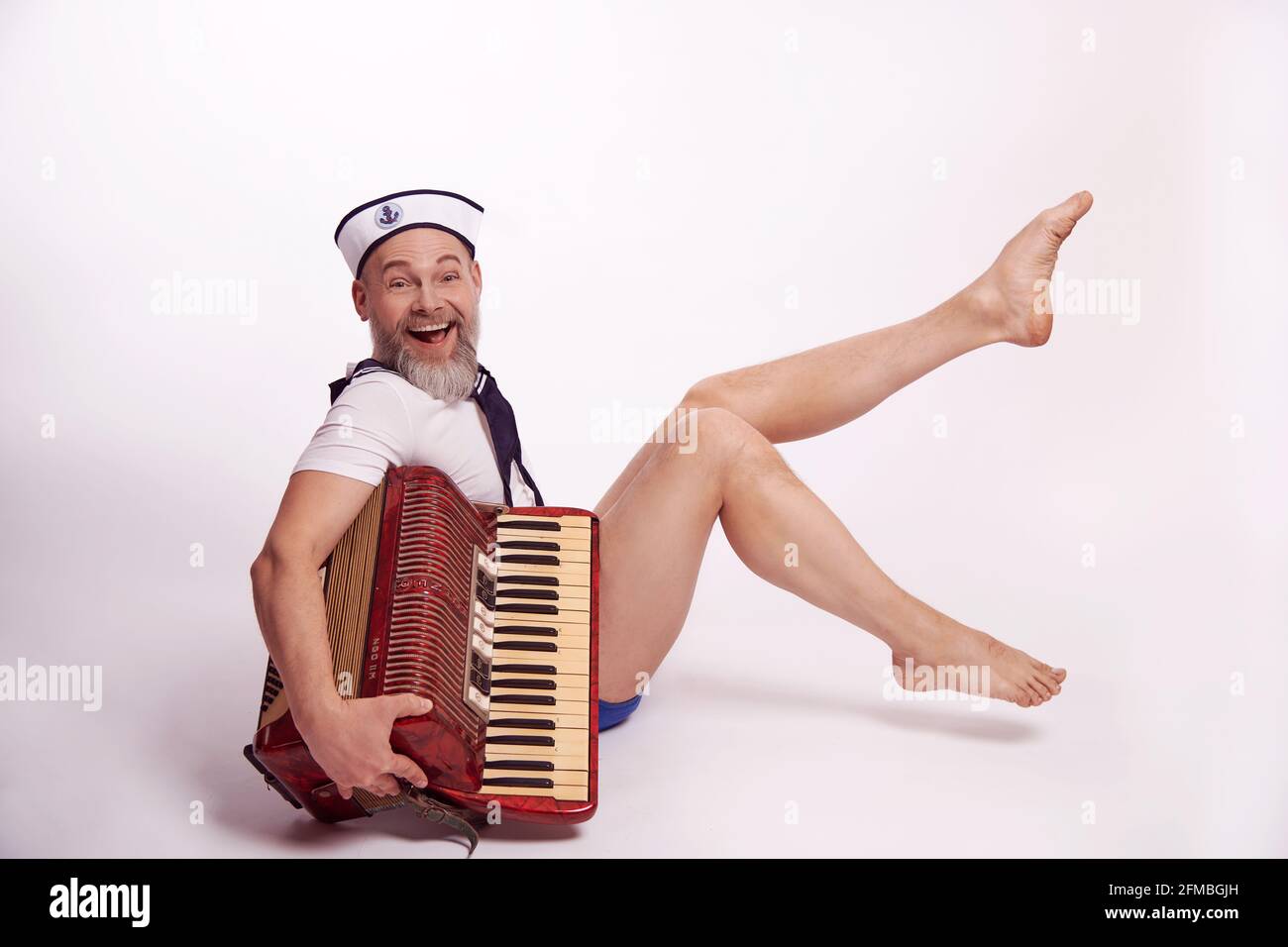 Homme avec une barbe complète comme marin de petit garçon dans un regard maritime avec un accordéon Banque D'Images