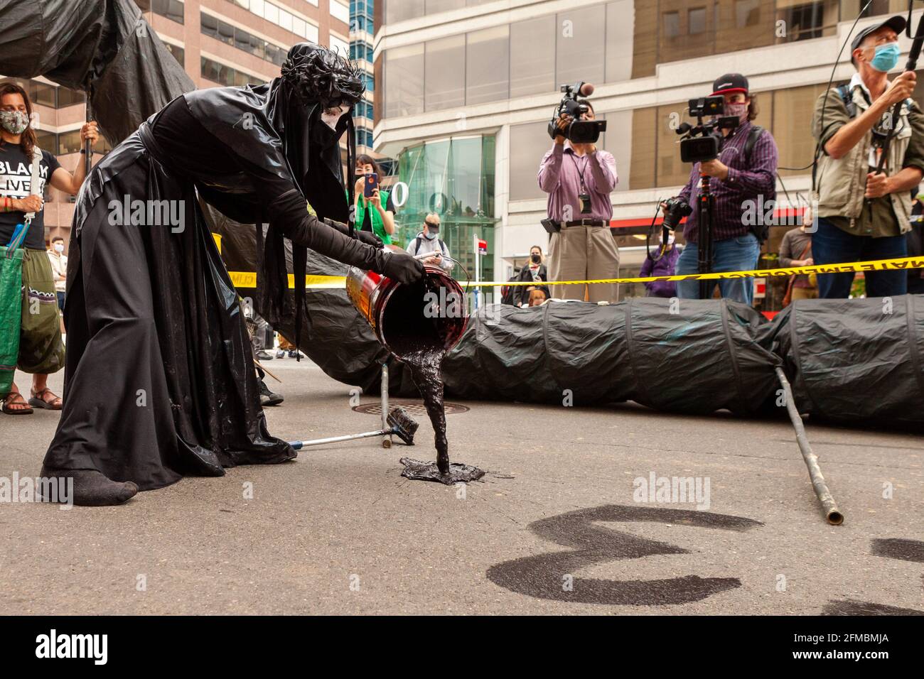 Washington, DC, États-Unis, 7;mai 2021. En photo : un membre noir de la brigade rouge de Rebellion utilise du pétrole pour écrire « Stop Line 3 » dans la rue lors d'une manifestation contre Wells Fargo exigeant de cesser de financer la construction du pipeline. La ligne 3 transportera de l'huile provenant des sables bitumineux du Canada. Crédit : Allison C Bailey / Alamy Live News Banque D'Images