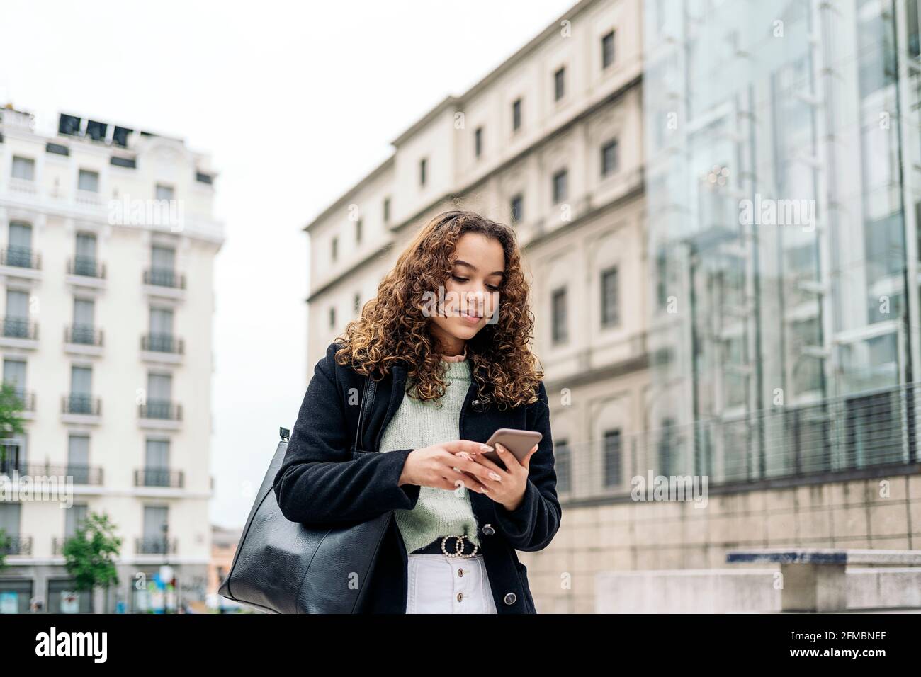 Jeune femme latine utilisant son smartphone dans la rue Banque D'Images