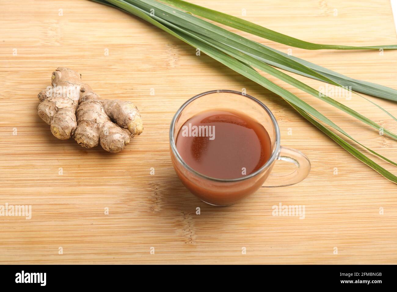 Verre de thé au gingembre chaud avec rhizome au gingembre (racine) tranché sur fond blanc. Banque D'Images