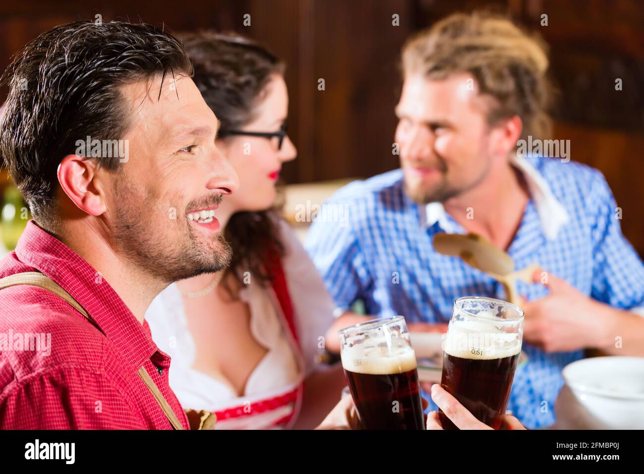 Les jeunes dans le style bavarois Tracht mange avec des saucisses au restaurant ou au pub le déjeuner ou le dîner Banque D'Images