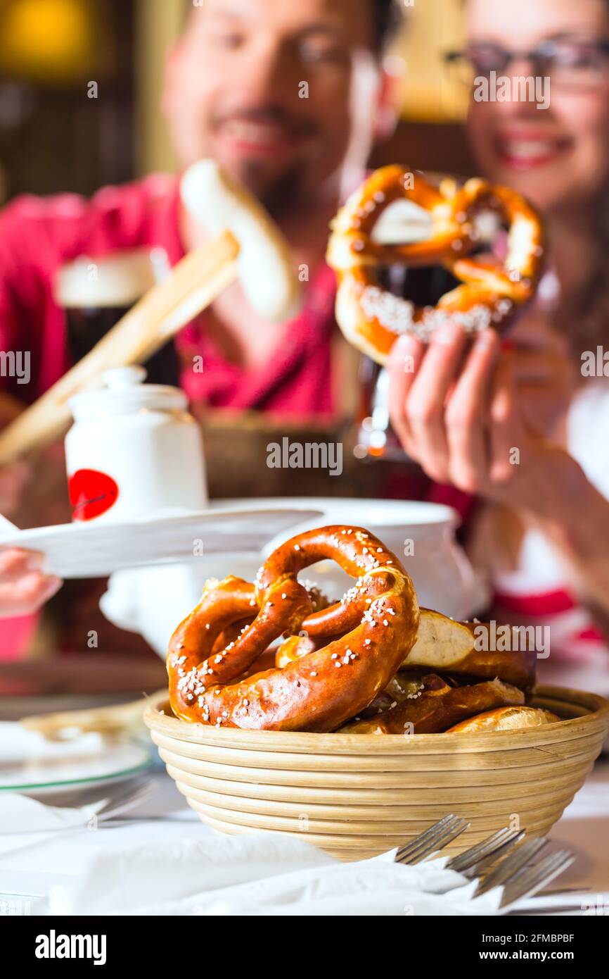 Les jeunes dans le style bavarois Tracht mange avec des saucisses au restaurant ou au pub le déjeuner ou le dîner Banque D'Images