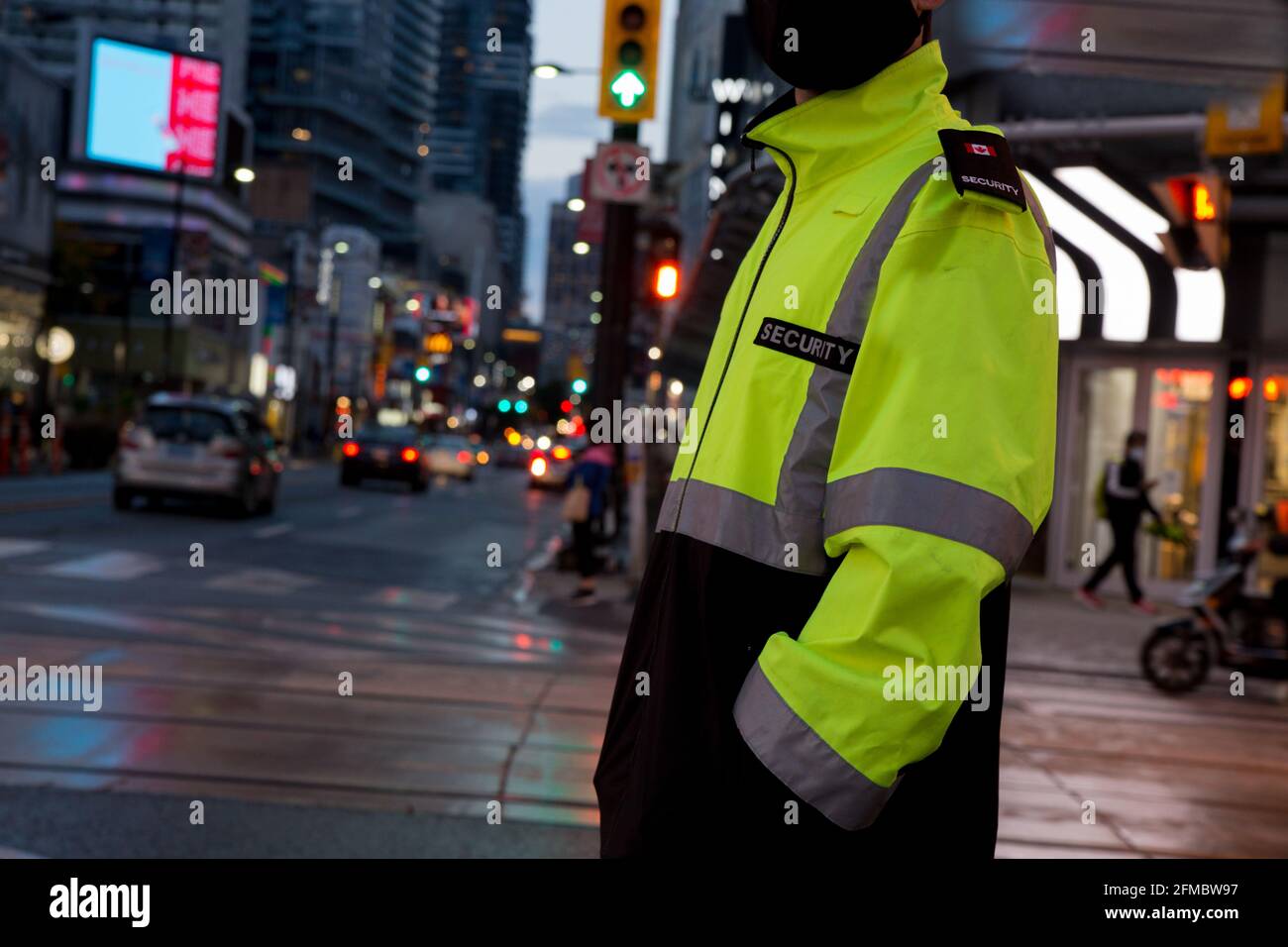 Vue d'un agent de sécurité qui patrouille dans une rue et une ville fréquentées avant le coucher du soleil. Banque D'Images