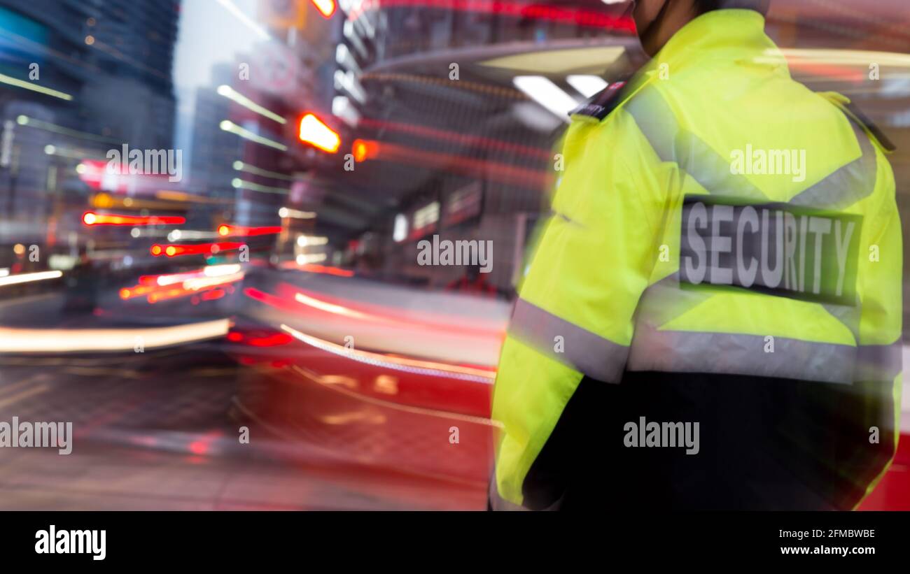 Un agent de sécurité routière dans un blouson vert clair patrouilant dans la rue avant l'heure du coucher du soleil. Banque D'Images