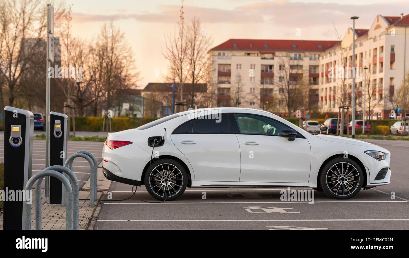 Une voiture électrique de la gamme de prix supérieure à un station de charge au coucher du soleil Banque D'Images