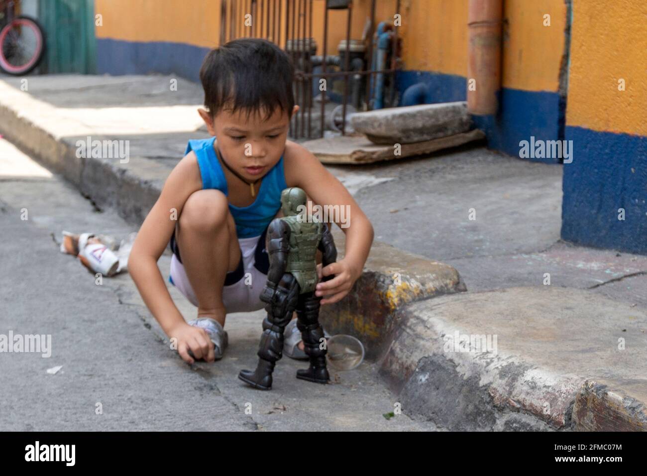 Garçon jouant avec le jouet dans la rue, quartier pauvre de Manille, Philippines Banque D'Images