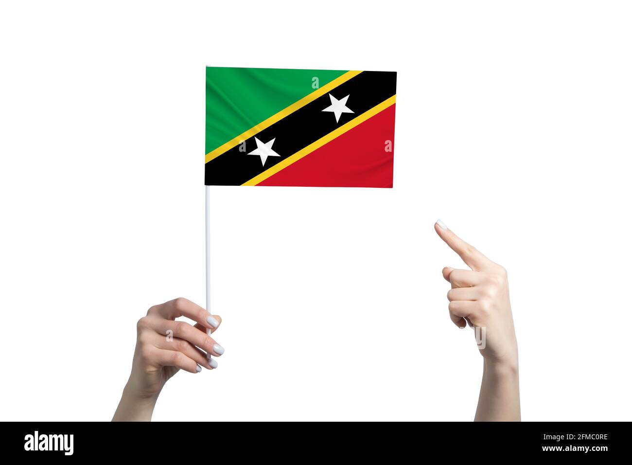 Une belle main féminine porte un drapeau de Saint-Kitts-et-Nevis, à lequel elle montre le doigt de son autre main, isolé sur fond blanc. Banque D'Images