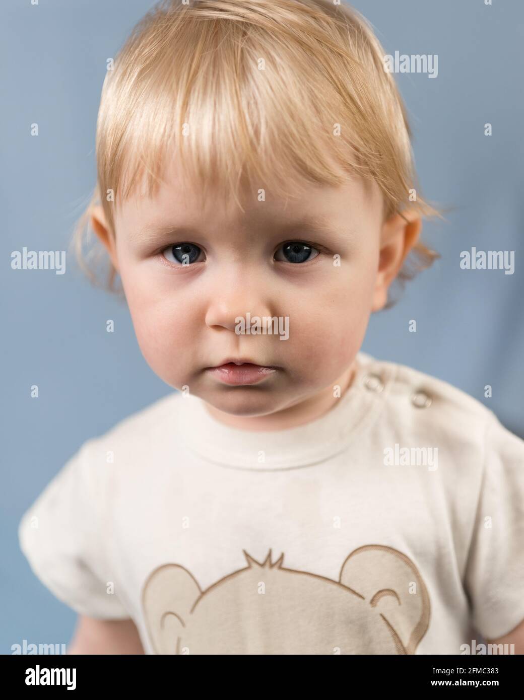 Portrait en gros plan d'une fille blonde âgée de 1 an. Le regard sérieux d'un enfant aux yeux bleus Banque D'Images