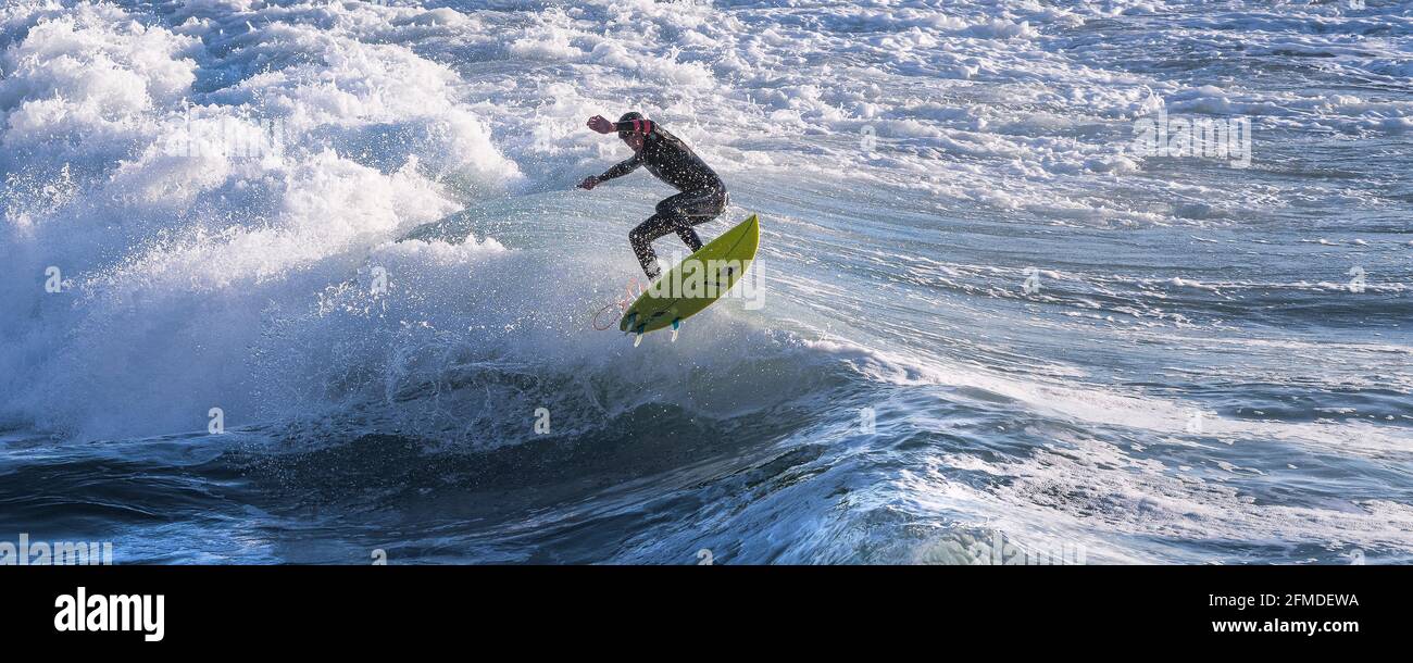 Une image panoramique d'un surfeur qui fait l'air d'une vague à Fistral, à Newquay, en Cornouailles. Banque D'Images