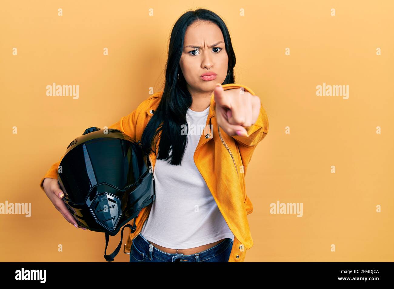 Belle femme hispanique avec piercing nez tenant casque de moto pointant  avec le doigt vers l'appareil photo et à vous, geste confiant regardant  sérieux Photo Stock - Alamy