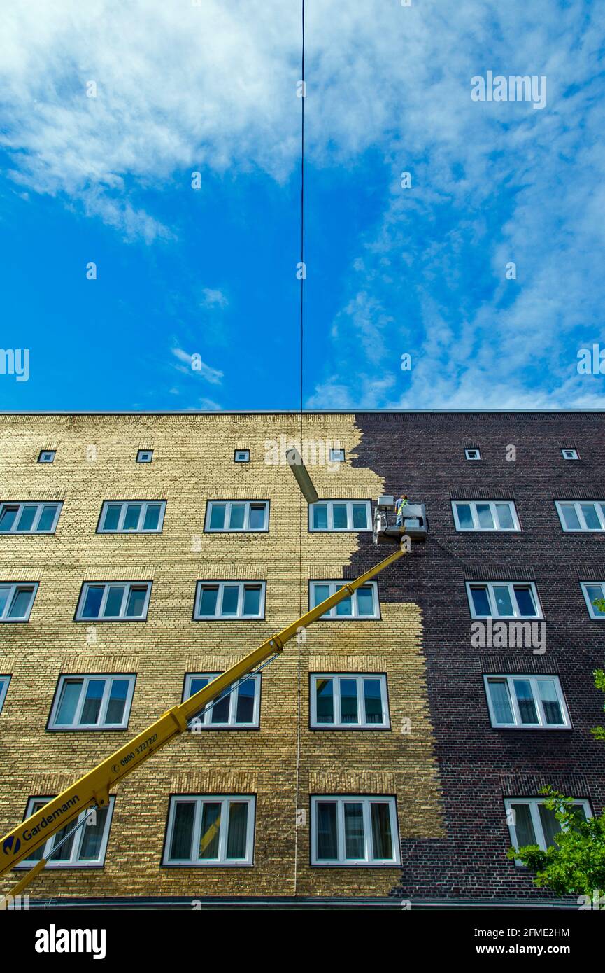 Künstler Boran Burchhardt trägt hauchdünnes Blattgold mit einem Spezialkleber auf eine 300 Quadratmeter große Hauswand à Hamburg-Veddel auf. Banque D'Images