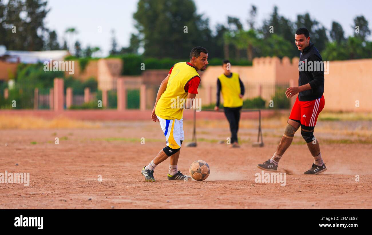 Marrakech, Maroc - 25 AVRIL 2021 : hommes jouant au football sur un terrain poussiéreux Marrakech au Maroc Banque D'Images