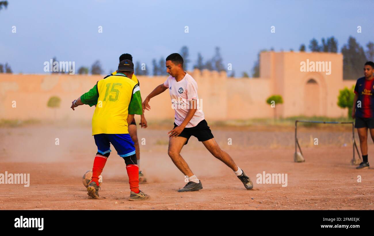 Marrakech, Maroc - 25 AVRIL 2021 : hommes jouant au football sur un terrain poussiéreux Marrakech au Maroc Banque D'Images Marrakech, Maroc - 25 AVRIL 2021 : hommes jouant au football sur un terrain poussiéreux Marrakech au Maroc Banque D'Images