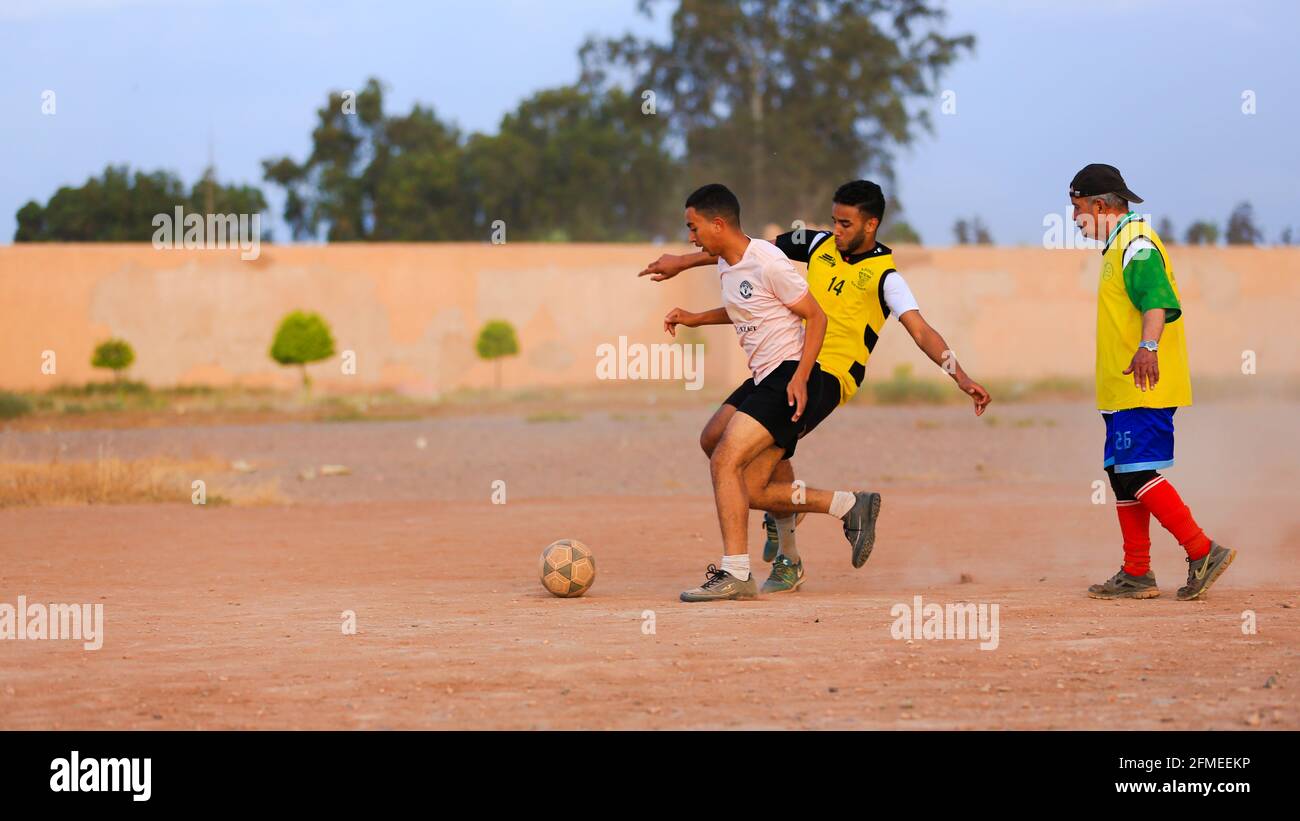 Marrakech, Maroc - 25 AVRIL 2021 : hommes jouant au football sur un terrain poussiéreux Marrakech au Maroc Banque D'Images Marrakech, Maroc - 25 AVRIL 2021 : hommes jouant au football sur un terrain poussiéreux Marrakech au Maroc Banque D'Images