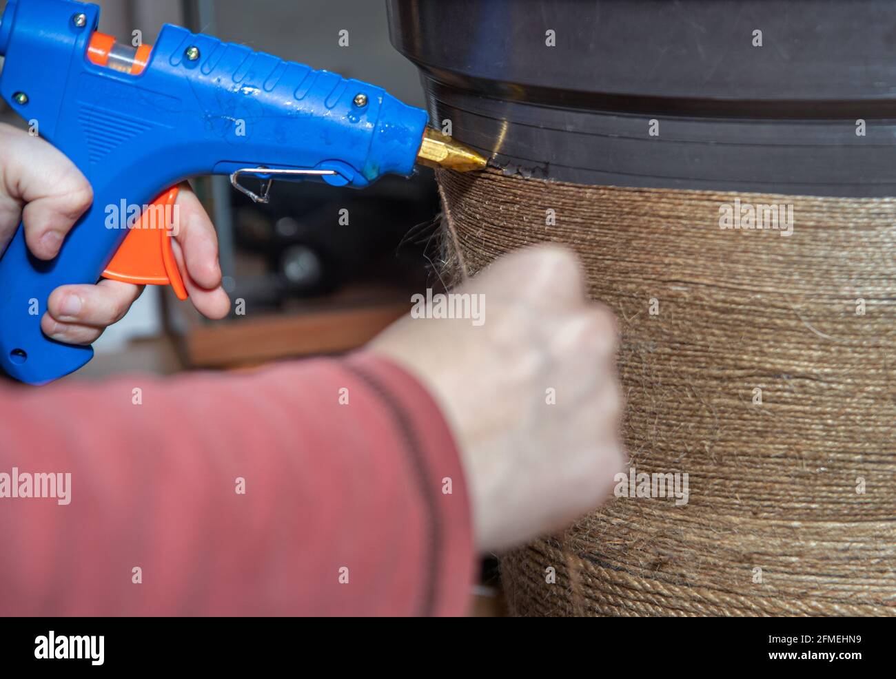 Gros plan de l'artisan, l'artiste fixe la décoration de corde sur le grand pot de fleur en plastique. Banque D'Images