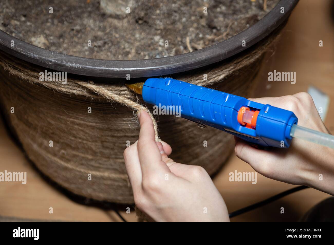 Gros plan de l'artisan, l'artiste fixe la décoration de corde sur le grand pot de fleur en plastique. Banque D'Images